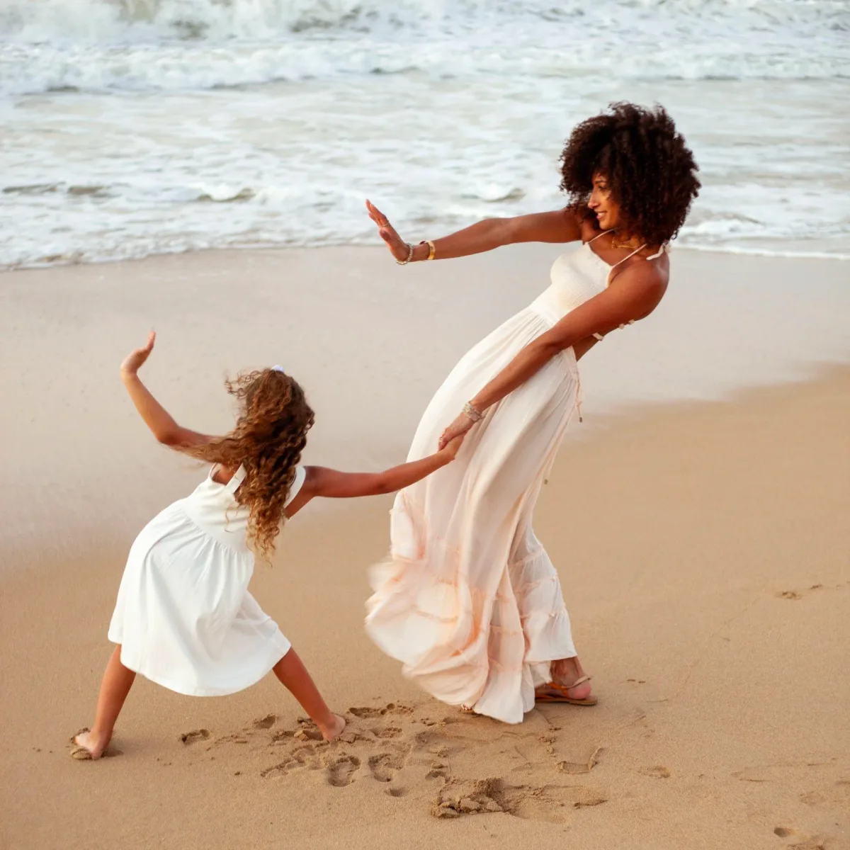 A mother and daughter dancing on the beach